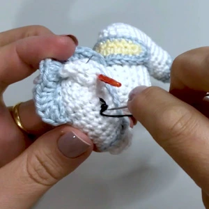 Mãos tecendo peça branca de amigurumi com marcadores de ponto