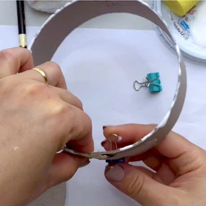 Mão pintando de branco a base de papelão do carrossel