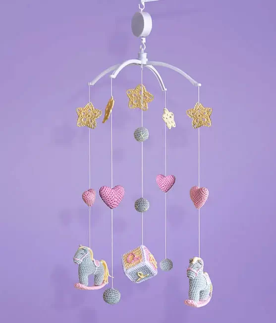 Móbile de amigurumi completo pendurado, com cavalinhos, estrelas, corações e um cubo